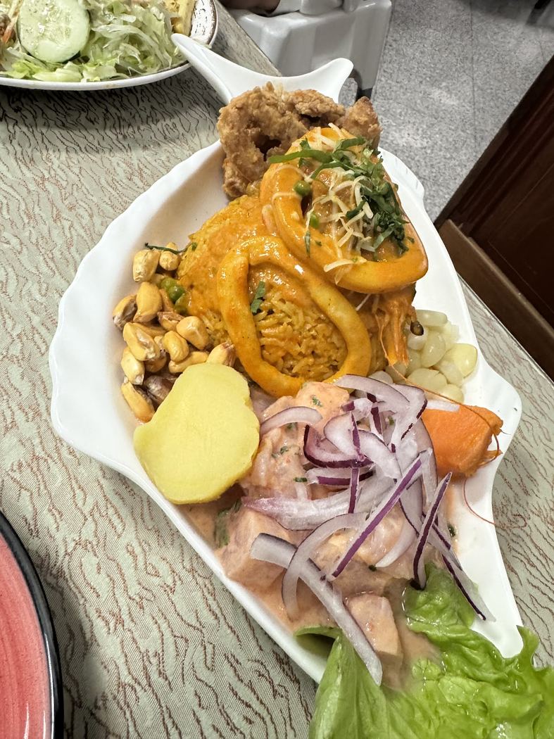 Ají de Gallina, gallina desmenuzada en crema de ají amarillo, servida con arroz y patata.